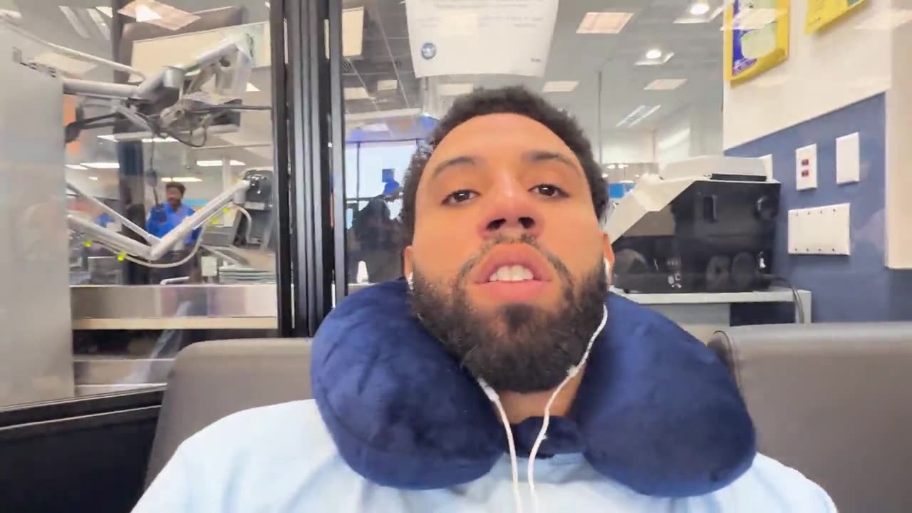 Calvin Priice at the airport with a travel neck pillow, filming episode one of the vlog